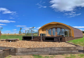 Glamping-pod ved navn Mingle Dale i Storbritannien, med trægulv, terrasse og klar blå himmel.
