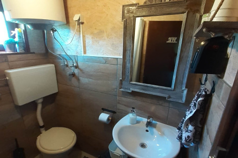 Compacte badkamer in een chalet, met toilet, lavabo, spiegel, boiler en betegelde muren.
