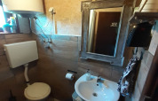 Piccolo bagno in uno chalet con WC, lavandino, specchio, scaldabagno e pareti piastrellate.