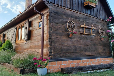 Charming wooden chalet in Croatia, decorated with flowerpots and wagon wheels on the exterior wall.
