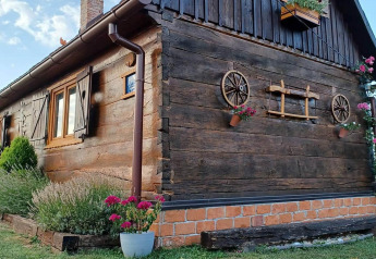Charming wooden chalet in Croatia, decorated with flowerpots and wagon wheels on the exterior wall.