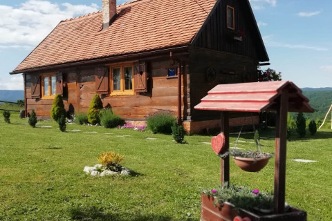 Stara Hiža Vlašić chalet with private garden, wooden cabin, greenery, and potted flowers in foreground.