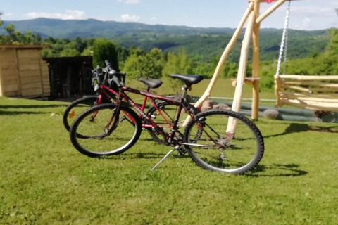 Two bicycles on grass with a swing and mountain view at Stara Hiža Vlašić chalet, Croatia.