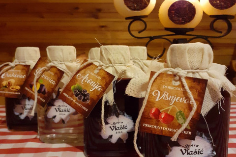 Homemade liqueurs in bottles with fabric covers and tags at Stara Hiža Vlašić chalet, Croatia, on a table.