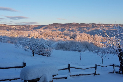 Sneeuwlandschap bij Stara Hiža Vlašić chalet in Kroatië met besneeuwde bomen en heuvels bij zonlicht.