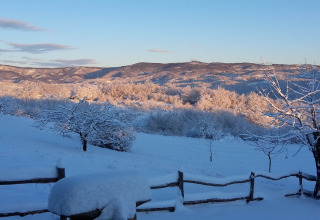 Sneeuwlandschap bij Stara Hiža Vlašić chalet in Kroatië met besneeuwde bomen en heuvels bij zonlicht.