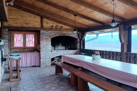 Sfeervolle chalet-eetruimte met houten dak, open haard, geruite tafeldoek en uitzicht in Kroatië.