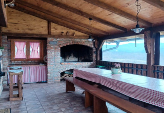 Landelijke chalet-eetkamer met houten plafond, open haard, geblokt tafelkleed en uitzicht in Kroatië.