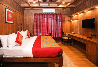 Habitación de madera en Ekta Houseboat Statue Of Unity con cama doble, decoración colorida y televisor.