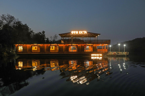 Vista nocturna del Ekta Houseboat iluminado en Statue of Unity Kevadia, reflejado en el agua tranquila.