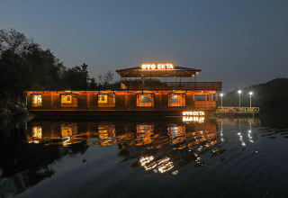 Vista nocturna del Ekta Houseboat iluminado en Statue of Unity Kevadia, reflejado en el agua tranquila.
