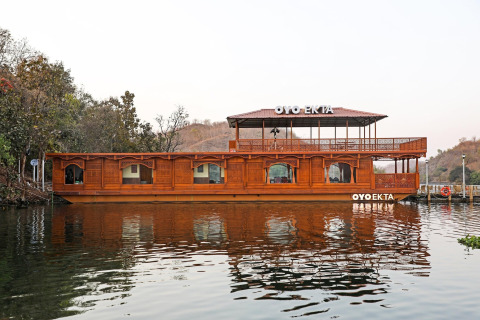 Ein Foto des Ekta Houseboats bei der Statue of Unity in Kevadia, mit kunstvollem Holzdesign am Wasser.