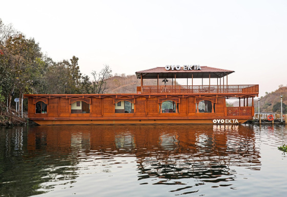 Foto della Ekta Houseboat vicino alla Statua dell’Unità a Kevadia, con elegante design in legno sull’acqua.