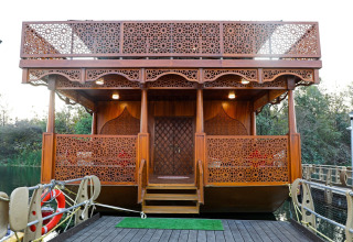 Vista frontal de Ekta Houseboat Statue Of Unity Kevadia, con tallados de madera ornamentados y escaleras.