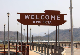 Willkommensschild am Ekta Houseboat bei der Statue of Unity, umgeben von Bergen und Gehweg.