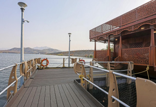 Vista de una casa flotante decorada en el muelle junto al agua y montañas cerca de la Estatua de la Unidad.