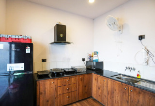 Cucina moderna sulla Ekta Houseboat Statue Of Unity Kevadia con frigo nero, lavello e ventilatore.