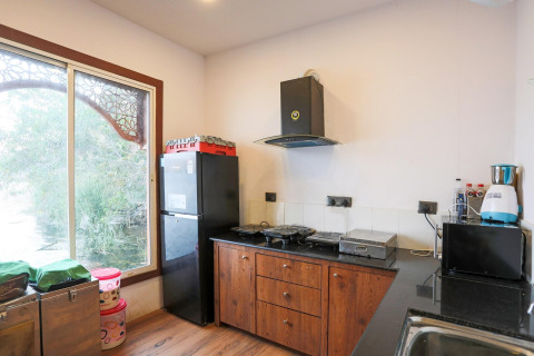 Helles Kücheninterieur eines Hausbootes mit Kühlschrank, Holzschränken und großem Fenster mit Aussicht.