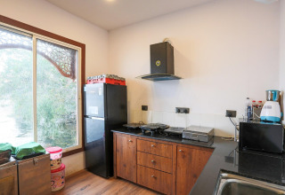 Helles Kücheninterieur eines Hausbootes mit Kühlschrank, Holzschränken und großem Fenster mit Aussicht.