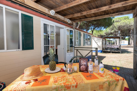 Buiten terras bij stacaravan Luna Pineta in Italië, met tafel vol fruit, snacks en drankjes.