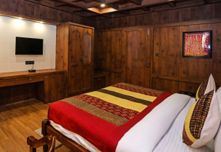 Dormitorio moderno en Ekta Houseboat Statue of Unity Kevadia con paredes de madera y ropa de cama colorida.