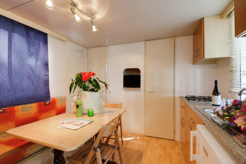 Lichte keuken en eethoek in het Luna Pineta mobiele huis in Italië, met planten en verse bloemen.
