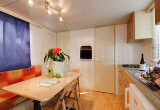 Lichte keuken en eethoek in het Luna Pineta mobiele huis in Italië, met planten en verse bloemen.