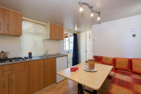 Interieur van een stacaravan met keuken en eethoek in Luna Pineta, Italië. Comfortabel en licht ingericht.