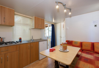 Interieur van een stacaravan met keuken en eethoek in Luna Pineta, Italië. Comfortabel en licht ingericht.