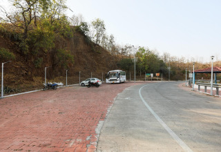Area parcheggio vicino a Ekta Houseboat Statue Of Unity Kevadia con autobus, auto e vegetazione circostante.