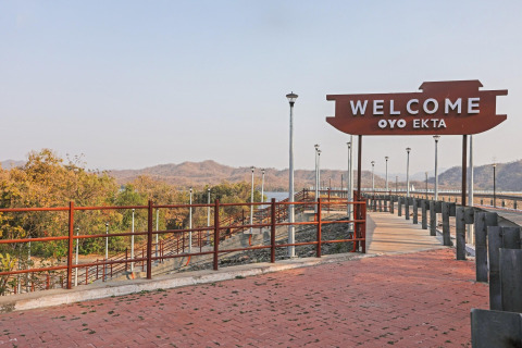 Cartello di benvenuto alla Ekta Houseboat Statue of Unity Kevadia, con paesaggio collinare sullo sfondo.