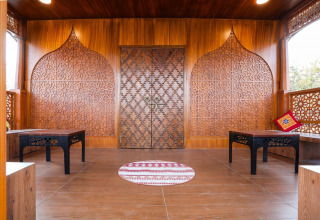 Traditionell verziertes Holzinterieur im Ekta Houseboat Statue Of Unity Kevadia mit kunstvollen Mustern und Tischen.