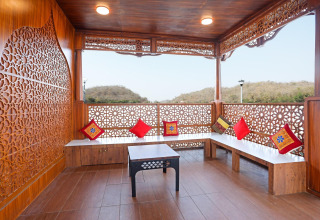 Veranda in legno su Ekta Houseboat Statue Of Unity Kevadia con cuscini vivaci e vista panoramica sulle colline.