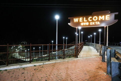 Insegna luminosa 'Welcome OYO EKTA' di notte su una passerella vicino alla Statue of Unity, India.
