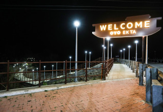 Letrero iluminado 'Welcome OYO EKTA' de noche en un paseo peatonal cerca de Statue of Unity, India.