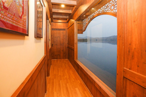 Corridoio in legno su Ekta Houseboat Statue Of Unity Kevadia con ampia finestra vista lago a destra.