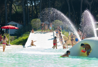 Kinderen spelen in het waterpark bij mobilhome Luna Pineta in Italië, met glijbanen en waterstralen.