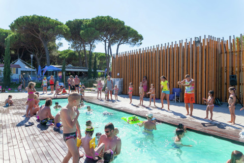 Kinderen en volwassenen genieten van activiteiten bij het zwembad bij Luna Pineta mobilhome in Italië.