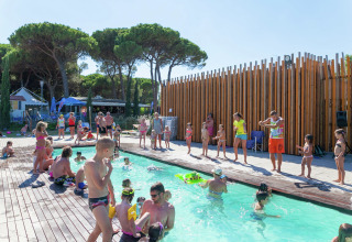 Kinderen en volwassenen genieten van activiteiten bij het zwembad bij Luna Pineta mobilhome in Italië.