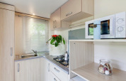Pequeña cocina moderna en mobil home Cottage Cesenatico, Italia, con fregadero, estufa y microondas.