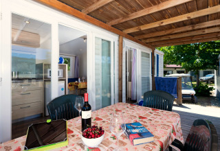 Terrasse des Mobilheims Cottage „Cesenatico“ in Italien mit gedecktem Tisch, Wein und idyllischer Aussicht.
