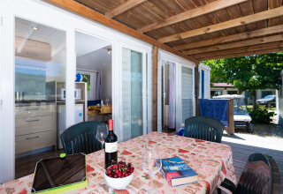 Terrasse des Mobilheims Cottage „Cesenatico“ in Italien mit gedecktem Tisch, Wein und idyllischer Aussicht.