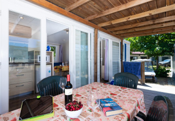 Udendørs spiseområde på mobilhome Cottage 'Cesenatico' i Italien med vin, kirsebær og terrasse.