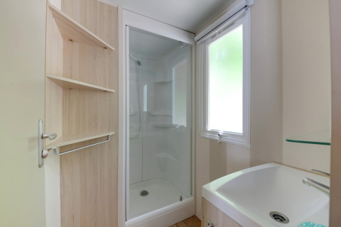 Badezimmer im Mobilheim Cottage «Cesenatico» in Italien mit Dusche, Waschbecken und Regal.