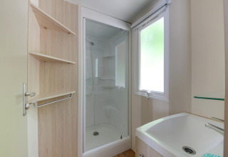Badezimmer im Mobilheim Cottage «Cesenatico» in Italien mit Dusche, Waschbecken und Regal.