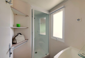 Badkamer in mobilhome Cottage «Cesenatico» in Italië met douche, planken en matglasraam.