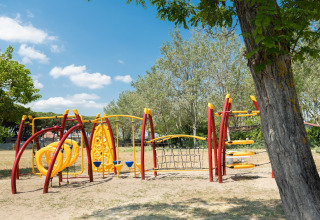 Parque infantil con modernos juegos amarillos y rojos en Cottage «Cesenatico», una casa móvil en Italia.