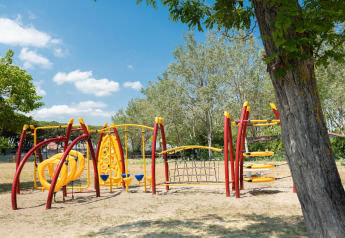 Parque infantil con modernos juegos amarillos y rojos en Cottage «Cesenatico», una casa móvil en Italia.