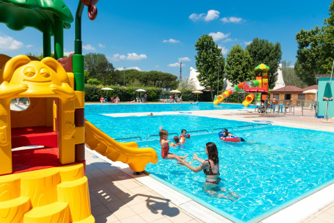 Niños jugando en una piscina al aire libre con toboganes en Cottage Cesenatico, Italia, en un día soleado.