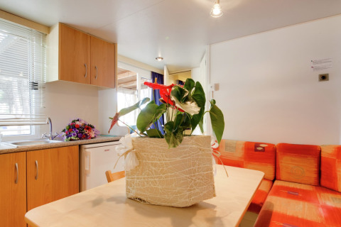 Interieur van de Luna Pineta stacaravan in Italië met gezellige keuken en bloemen als tafeldecoratie.